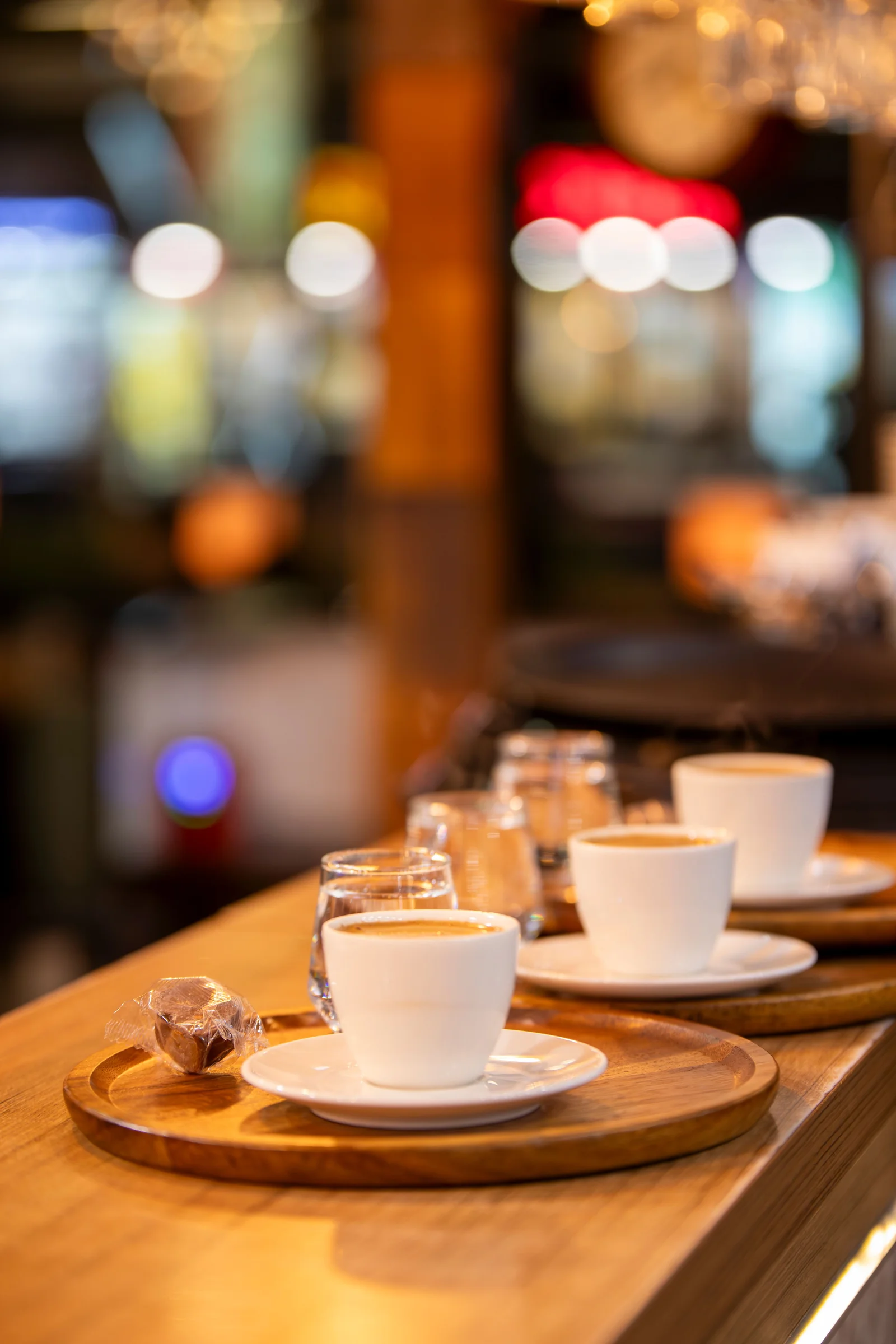 Small cups of coffee lined up on a warm wooden counter