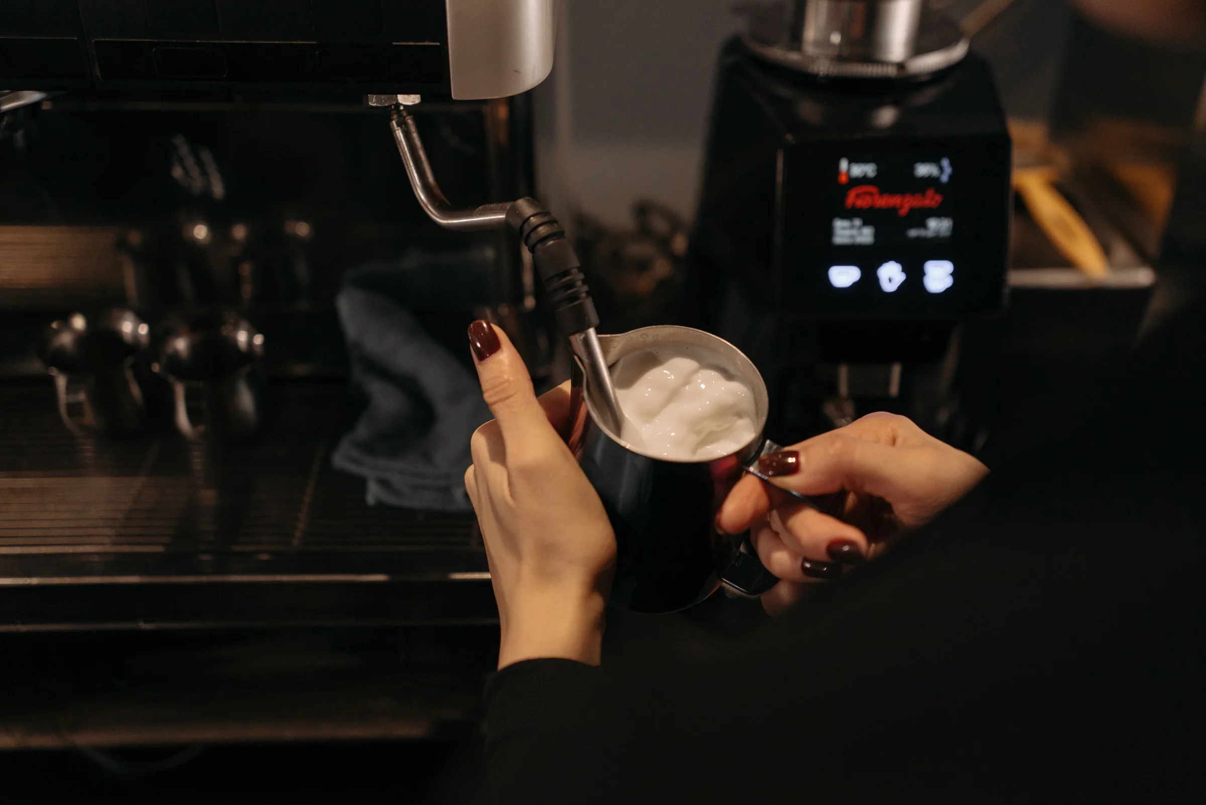 A barista steaming milk at an espresso machine